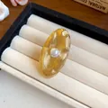 Dettaglio ravvicinato di orecchini a lobo ovali dorati con perla centrale. - Anello aperto regolabile / Oro