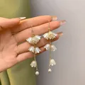 Eleganti orecchini lunghi a nappa mughetto con perle bianche e una catena dorata. - Stile Mughetto