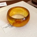 Macro view showing the translucent amber marbled texture of a chunky resin wide bangle - Coffee Wide Style (10#)