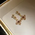 Nahaufnahme von Vintage-Ohrringen mit Strassblumen und rotem Edelstein in der Mitte - Ohrringe / Goldbraun
