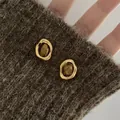 Orecchini vintage occhio di tigre placcati oro su sfondo di maglia marrone. - Stile Occhio di Tigre Ovale