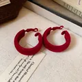Detailed macro view of wine red flocked hoop earrings with elegant soft velvet texture. - Red