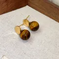 Primo piano di orecchini a lobo rétro in occhio di tigre con placcatura in oro e trama. - Stile Sfera Rotonda Semplice (HE29420)