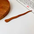 Macro detail of a wavy peach wood hair stick with a fine perforation on the end - Dark Coffee