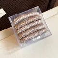 Close-up of 5-piece set of champagne fabric hair ties in a clear square box - Five-Piece Set / Light Gray