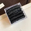 Close-up of five black pleated fabric hair scrunchies in a clear square storage box - Five-Piece Set / Black