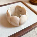 Macro view of a chunky cream marbled acrylic stretch bracelet on white linen background - Marble Wide Bangle (HB4269) / White