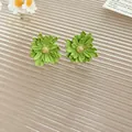 Detailed view of matte green resin flower stud earrings with gold center on glass - 23# Matte Daisy Lacquered Style / Grass Green-Gold