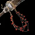 Vue détaillée d'un élégant collier doré multicouche avec des pierres de zircon rouges - Or-Rouge