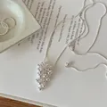 Close-up of silver beaded cluster pendant necklace on an artistic paper background - Silver