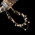 Gros plan d'un collier multicouche en perles dorées avec cristaux de zircone ronds - Or-Blanc