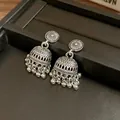 Primo piano di orecchini jhumka in argento vintage con incisioni e pendenti a pallina - Argento