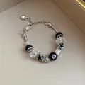 Close-up detail of a silver snake chain bracelet with black star charms and 8-ball bead - Silver Black