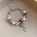 Detailed close-up of a pink glass bead charm bracelet with flower and bow pendants. - Silver Pink
