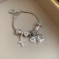 Detailed macro view of a silver charm bracelet with heart and cross pendants - Silver