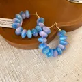 Macro view of translucent blue and purple resin beads on silver needle hoop earrings. - Blue-Pink