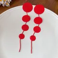 Detailed macro view showing the unique textured pattern of these red circular tassel earrings - Red