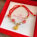 Detail of a red woven rope bracelet featuring glass beads and a gold rocking horse pendant - Hand-Braided Pearl Horse (Style 17)