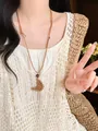 Close-up of bohemian woven croissant pendant necklace featuring brown cord on model - 18# Style - Moon Woven