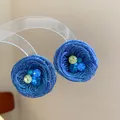 Makroansicht blauer gewebter Blumenohrstecker mit funkelnden mehrfarbigen Kristallen. - Gewebter Blumenstil