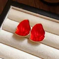 Primo piano dettagliato di orecchini in smalto rosso con finitura dorata in portagioie - Rosso