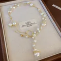 Close-up detail of a vintage-style necklace featuring irregular pearls and a gold pendant - Baroque Irregular Pearl Style / Gold