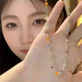 Detailed view of a colorful crystal bead necklace held by a female model. - Style 4 Necklace