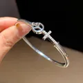 Detailed close-up of a silver-tone peace and cross bangle with cubic zirconia gems - Peace Cross Style (8)
