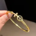 Close-up of 18k gold plated bangle with a sparkling zircon cross and peace symbol - Cross Peace Sign Style (7)