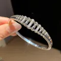 Close-up detail of silver geometric openwork bangle with sparkling inlaid zircon stones - Oval Hollow Pave Style (12)