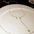 Close-up of adjustable gold snake chain necklace with pearl and bead tassels on white plate - Style 1 (HN3365)