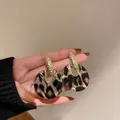 Dettaglio macro di eleganti orecchini geometrici leopardati con perni testurizzati dorati - Stile 5