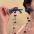 Pendientes de borlas bohemias rojas y azules usados por una modelo en vacaciones - Estilo 2