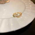 Primer plano de un anillo geométrico dorado con circonitas e incrustación de nácar blanco - Dorado (6#)