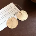Makro-Detail von eleganten goldenen runden Ohrhängern mit konzentrischer Spiralstruktur - Gold