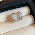 Vista detallada de pendientes de aro en C plateados con patrón de textura tejida. - Pequeño / Plateado