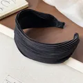 Close-up detail of a elegant black pleated fabric wide headband for high-crown styling - Black
