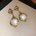 Detailansicht von goldenen Vintage-Blumenohrhängern mit großem Perlen-Cabochon-Akzent - Ohrringe / Gold