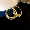 Macro detail of 18k gold plated double hoop earrings set with sparkling cubic zirconia - Gold