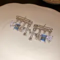 Detailed macro view of silver safety pin earrings with blue zircon and sparkling cross charms - Safety Pin Tassel Style (7#) / Silver