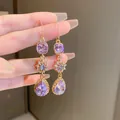 Detailed view of long purple teardrop dangle earrings with sparkling star zircon accents. - Ear Hook Style (15#) / Purple