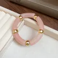 Detailed view of an elegant pink acrylic tube bracelet with polished gold spacers - Peach Pink