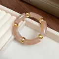 Detailed close-up of a vintage marbled acrylic segment bracelet with gold bead accents - Brown