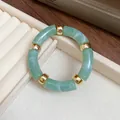 Macro view of green iridescent acrylic segments and gold spacers on retro fashion bracelet - Green