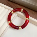 Macro detail of red marbled acrylic segments and golden metal spacers on this retro bracelet - Dark Red