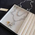 Détail d'un collier pendentif cheval en argent poli avec des perles grises dans un plateau - Gris-Argent-Brillant