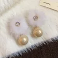 Primo piano di eleganti orecchini a pompon in peluche con zirconi e dettagli in perla - Bianco