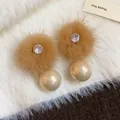 Dettaglio macro di eleganti orecchini invernali con palline di pelo e perle champagne - Marrone