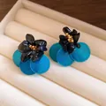 Primo piano di orecchini vintage con petali in conchiglia blu e accenti in pietra nera. - Stile del Fiore (HE29306) / Blu