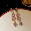 Primo piano di orecchini vintage dorati con cristalli rosa e strass luccicanti - Viola / Oro
